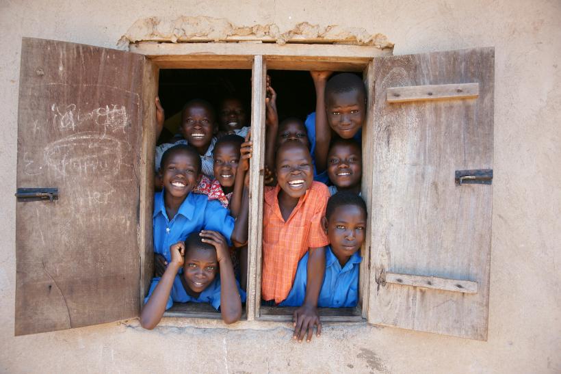 A group of young children standing in a window at a school in Uganda